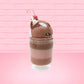 Cute kawaii bunny tall brown and light brown ice cream sundae with brown chocolate crumbles over the bunny, with a cherry on top of the whipped cream swirl.  Three bendy gummy worms are in the dish on the side. This view is from the other side.