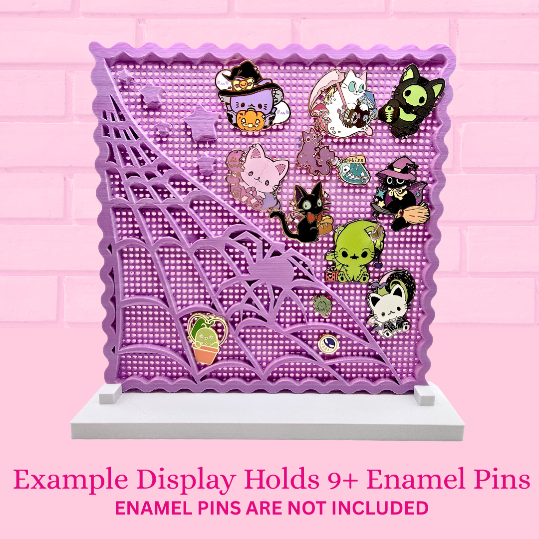 Spider web stamp pin board with 12 enamel pins, with the words Example Display holds 9+ enamel pins, enamel pins are not included.